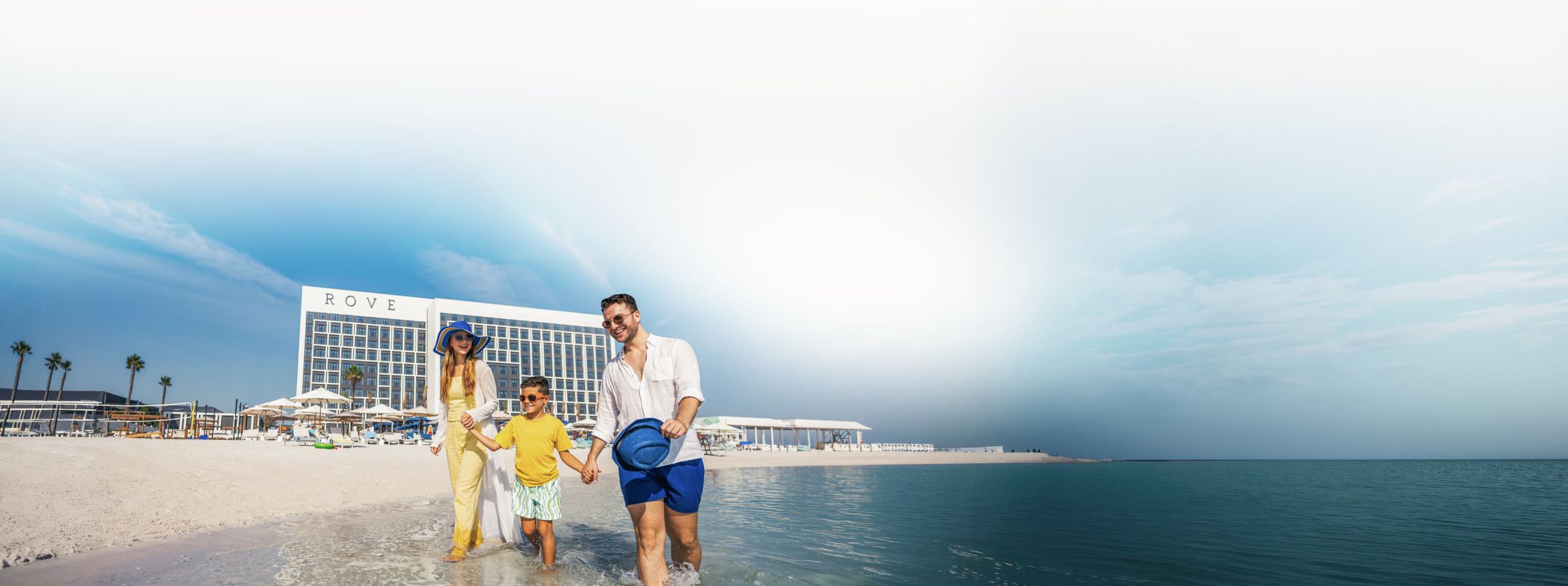 Family on the beach in front of a Rove hotel